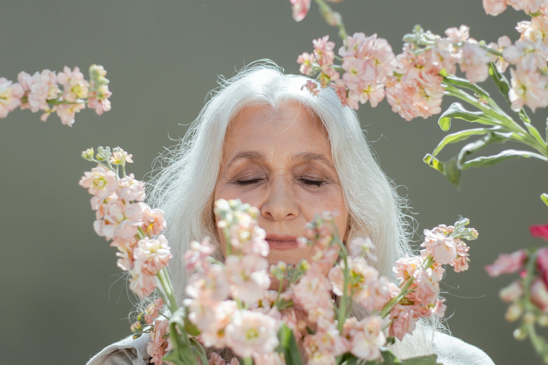 woman with white hair surrounded by white and pink flowers